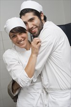 Bakers hugging in bakery kitchen