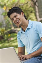 Hispanic man using laptop outdoors