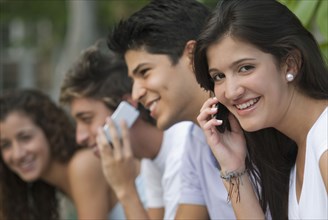 Hispanic woman talking on cell phone with friends in background