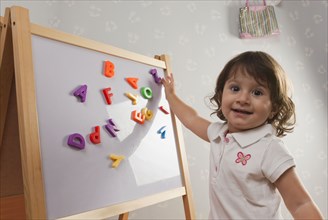 Hispanic baby playing with letters on magnetic board