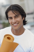 Hispanic man holding yoga mat