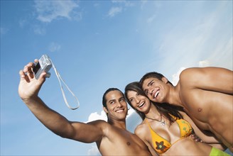 Friends in bathing suits taking self-portrait with digital camera