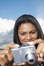 Black woman taking photograph with digital camera