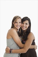 Smiling Hispanic sisters hugging