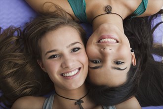 Smiling Hispanic sisters laying together