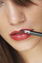 Caucasian woman putting on lipstick with brush