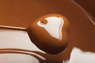 Heart-shaped candy being dipped in chocolate