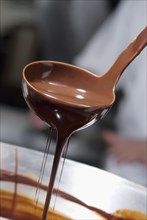 Melted chocolate dripping from ladle