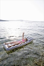 Caucasian girl floating on raft in lake