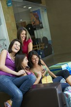 Hispanic friends text messaging on cell phone