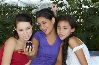Hispanic girls taking self-portrait with cell phone