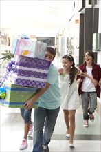 Hispanic friends carrying gifts in shopping mall