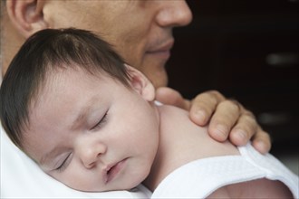 Hispanic father cuddling baby daughter