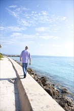 Hispanic man walking on wall near ocean
