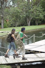 Hispanic couple walking on pier carrying fishing poles