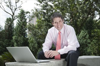 Hispanic businessman using laptop outdoors