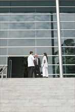 Hispanic business people talking to doctor on steps