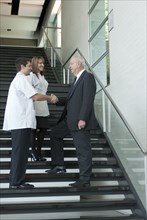 Hispanic businessman shaking hands with doctor on staircase