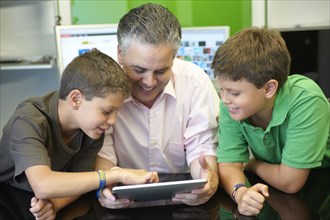 Hispanic father and sons using digital tablet