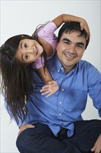 Smiling Hispanic girl leaning on father