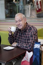 Senior Hispanic man drinking coffee in cafe
