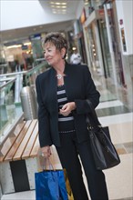 Senior Hispanic woman walking in mall with shopping bags