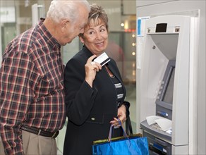 Senior Hispanic couple withdrawing money from ATM
