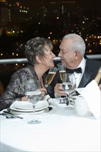 Senior Hispanic couple toasting with Champagne in restaurant