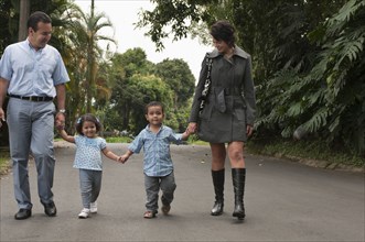 Hispanic parents holding children's hands outdoors