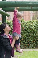 Hispanic mother helping daughter in playground