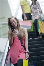 Hispanic woman text messaging on escalator