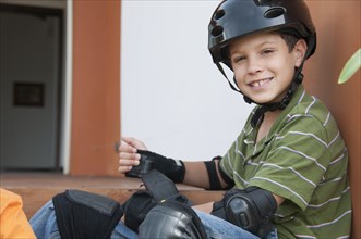 Hispanic boy in skateboard pads and helmet