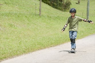 Hispanic boy riding skateboard on road