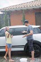 Rain falling on Hispanic couple washing car