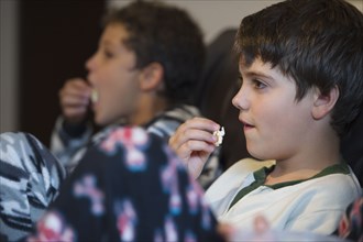 Hispanic boys eating popcorn and watching television