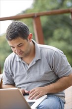 Hispanic man using laptop outdoors
