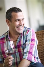 Smiling Hispanic man drinking wine