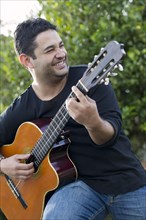 Smiling Hispanic man playing guitar
