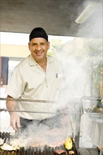 Hispanic man cooking food on barbecue grill