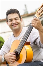 Smiling Hispanic man holding guitar