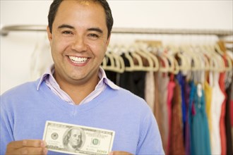 Hispanic man holding cash in clothing store