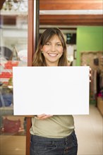 Hispanic woman holding blank sign in store