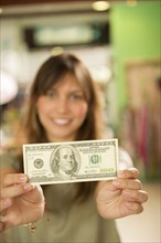 Hispanic woman holding cash in store