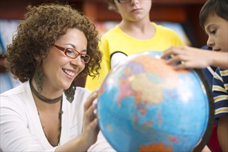 Hispanic teacher helping students with globe