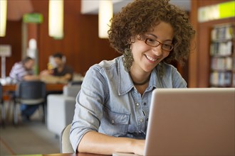 Hispanic woman using laptop in library