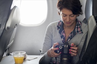 Hispanic woman using camera in airplane