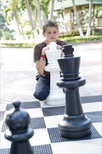 Hispanic boy playing with oversized chess set
