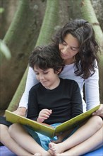Hispanic mother and son reading outdoors