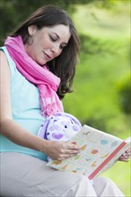 Pregnant Hispanic woman reading children's book