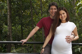 Mixed race expectant couple hugging outdoors